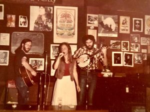 Mary singing in a band, early in her career. Shown in a cafe with a guitarist and a banjo player.