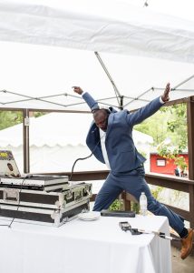 Justin James at his turntable but in mid-jump to the music (hands and legs in the air)
