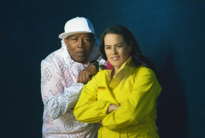 Man facing the camera wearing white hat and jacket. Next to him woman facing camera in yellow jacket.